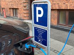Elbil lader ved p-skilt med vilkår for opladning af elbiler.