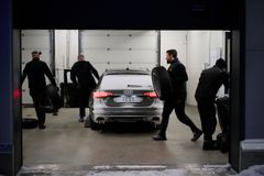 Testassistenter skifter hjul på mørk bil i garage