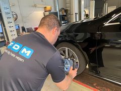 Testassistent fotograferer ridset fælg på sort bil
