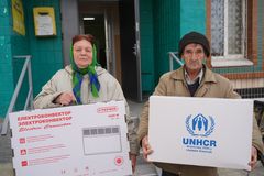 To personer holder UNHCR-udleverede kasser med termiske kits foran