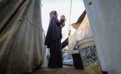 Inas, mor til tre børn, leger med sin nyfødte uden for sit telt i det vestlige Gaza City.