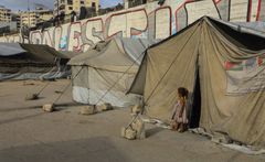 En pige står ved indgangen til sin families telt i en flygtningelejr i det vestlige Gaza City.