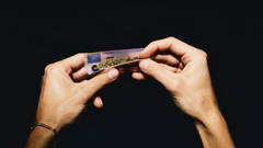 En hånd ruller en joint på rygepapir, der ligner et kørekort. Kampagnen "Lad ikke dit kørekort gå op i røg" fra Rådet for Sikker Trafik vil minde unge om, at de risikerer kørekortet, hvis de kører bil påvirket af cannabis.