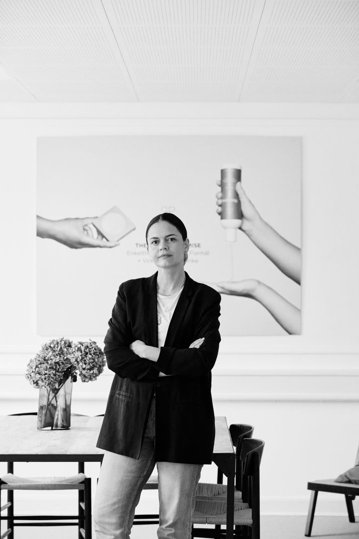 Person står foran et kunstværk, der viser hænder med produkter.