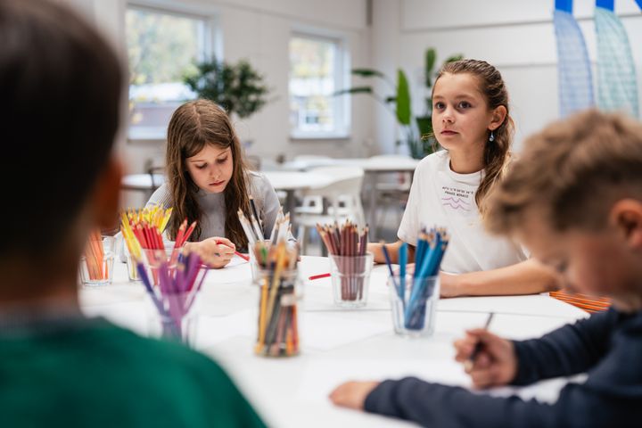 Børn sidder om et bord med farveblyanter som illustration på en nyhed om et nyt skriveværksted der åbner for Børn i Billund Kommune