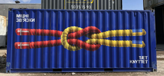 En blå skibscontainer med teksten Tæt Knyttet og billedet af et knob udført i henholdsvis de danske og ukrainiske farver.