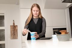 Billedet viser en ung kvinde, der åbner et bøger med hytteost.