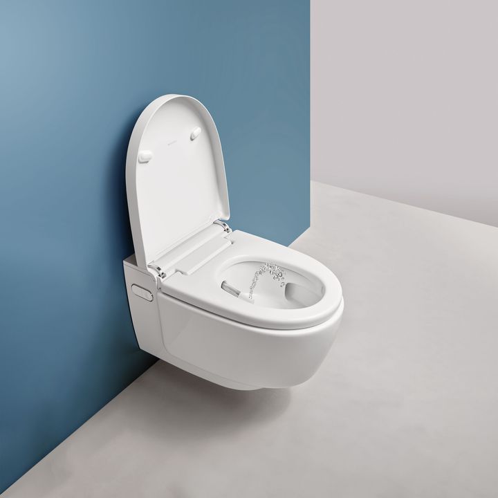 Vægmonteret hvid Geberit toilet mod blå væg.