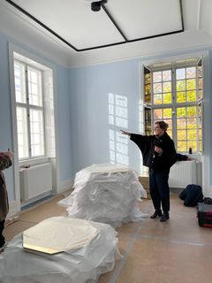 Formidlingsleder Rikke Johansen Smidt står i et rum med lyseblå vægge og fortæller om de kommende udstillingsrum.