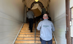 En gruppe arbejdere bærer dele af scenografi op ad den gamle trappe ved hovedindgangen til den tidligere Vestre Landsret i Viborg.