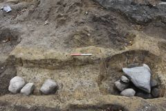 Arkæologisk udgravning med sten i jorden, viser fundamentrester fra en gammel trækirke inklusiv væggrøft og stolpehul.