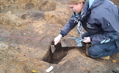 Arkæolog undersøger en udgravning med en murske på en arkæologisk udgravning.