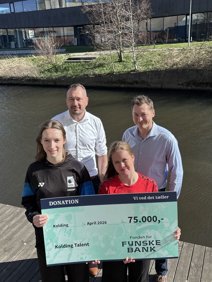 To piger holder et gavekort, mens to mænd står i baggrunden