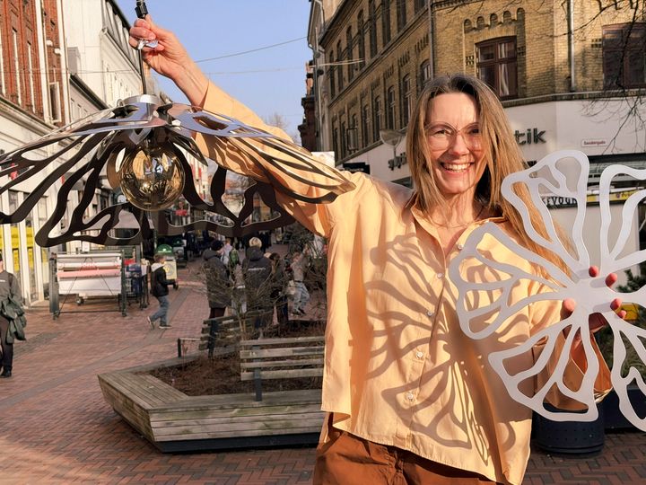 Designer Anne Mette Bjerre Hansen viser den nye sommerudsmykning, som består af en lampe og en blomst i sølv.