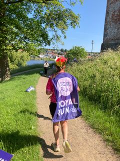 En person på en sti med kappe, hvor der står side run - Royal Run
