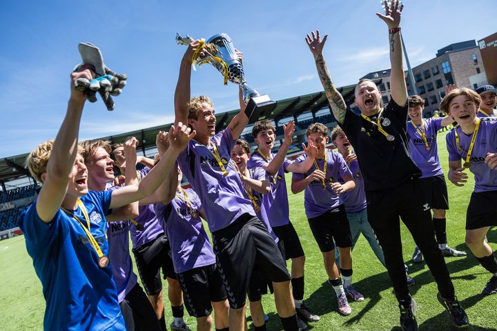 Fodboldspiller løfter en pokal mod himlen