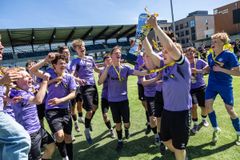 Fodboldspillere løfter pokal mod himlen.