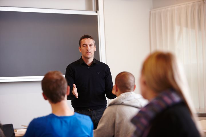 Mand ved tavle underviser tre elever