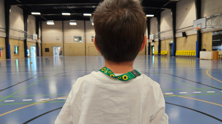 En dreng i en sportshal med ryggen til kameraet.