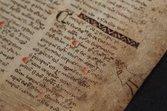 Gammel manuskriptside med håndskrevet tekst og dekorationer i rødt og sort.