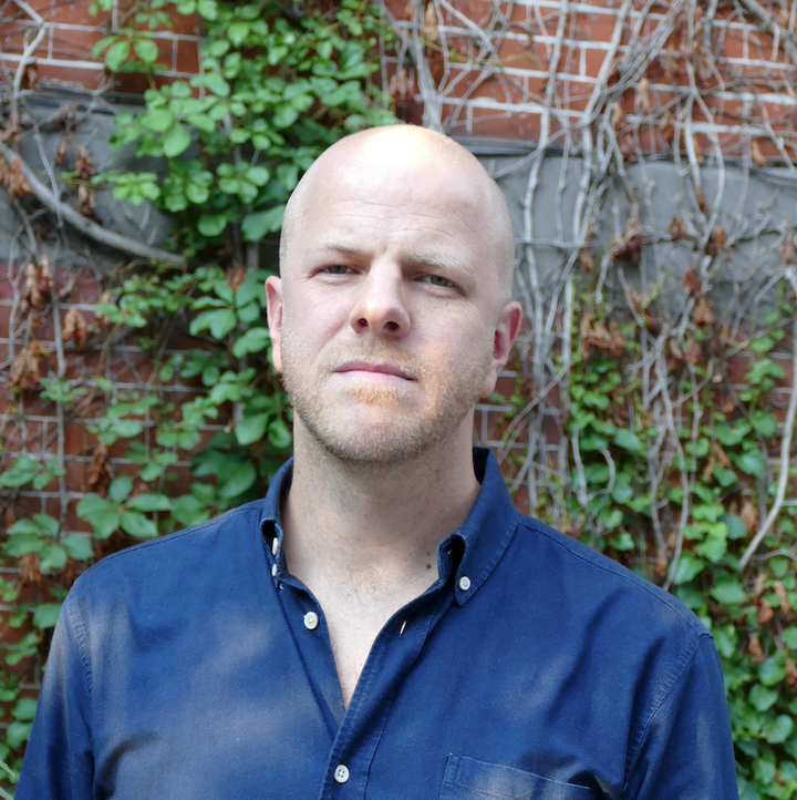 Martin Gelin foran en mur dækket af klatreplanter. Han bærer en mørkeblå skjorte.