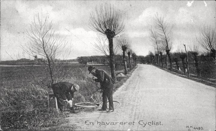 To mænd ved en landevej reparerer en cykel.