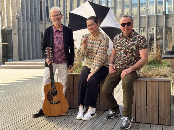 Peter Elmelund med guitar, Signe Winther Brinkmann med parply og Jens Sørens med solbriller - klar til at synge om måneden, der ikke kan bestemme sig for vejret.
