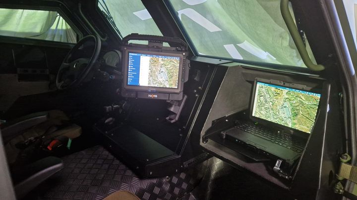 Armored vehicle interior featuring screens displaying maps and software.