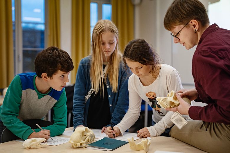 Tre børn og en ung kvinde fordyber sig i videnskaben om primater