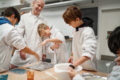 En gymnasieelev og en ung dreng i kitler står sammen om et videnskabeligt forsøg og griner