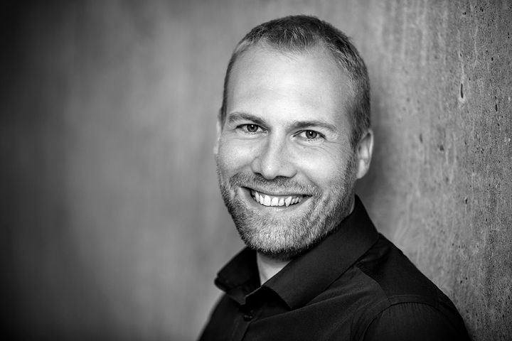 En mand smiler til kameraet, sort-hvid foto.