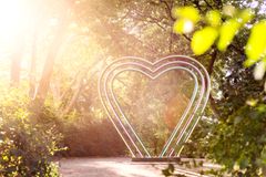 Metalskulptur af et hjerte i en solbelyst park.