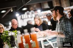 En mand taler med kunder ved en bod i Malmö Saluhall.