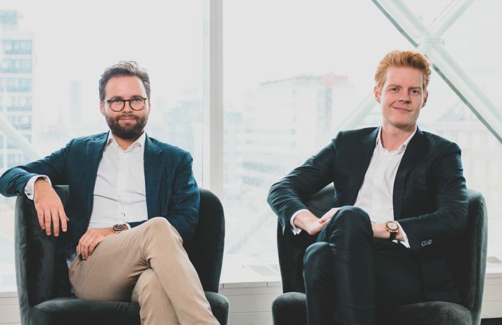 To personer sidder i stole i et kontormiljø.