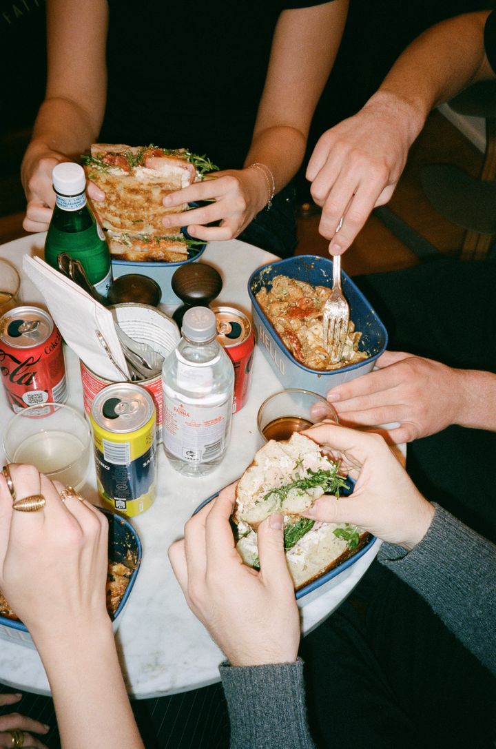 Venner deler pastaretter ved et bord med drikkevarer.