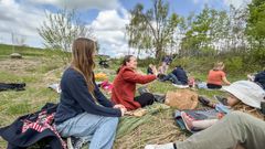 Kommende bofæller sidder på græsset på æblegårdsgrunden.