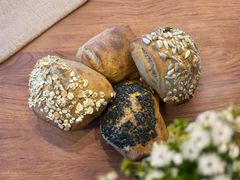 Fire forskellige Barleo stykker med frø og korn på en træbordplade.