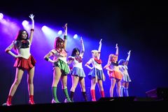 Seks udklædt dansere poserer på en scene.