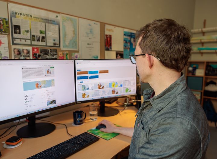 En mand sidder ved et skrivebord og arbejder på computeren.