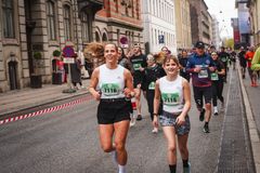 Smilende løbere med startnumre løber side om side gennem København