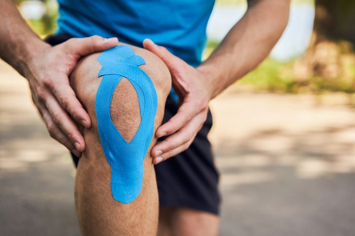 Person med blå kinesiologitape på knæet.