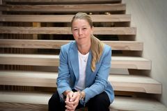 Agnete Kirk Kristiansen i lyseblå blazer sidder på en trappe og kigger mod kameraet.