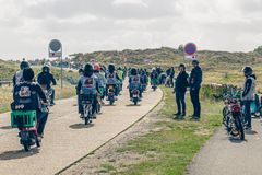 Massevis af knallerter kører på en ældre vej langs vestkysten på vej ud af en lille by.