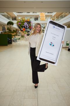 En glad Yasmin Lindharth holder blomster og en MobilePay-check op for at vise, at hun har modtaget årets fagprøvepris 2026.