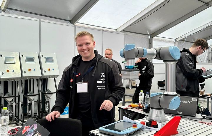En mand står ved siden af en robotarm ved ROBOTBRAG-læringsdagen. Foto: Danfoss.