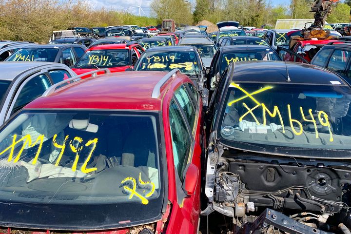 Billedet viser en større skrotplads med mange bjærgede biler, hvoraf mange har store gule numre skrevet på forruderne.
