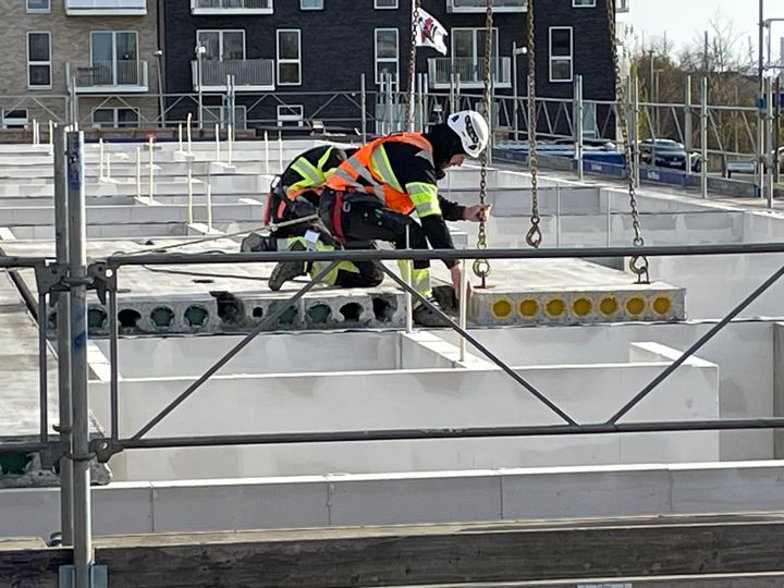 En arbejder monterer betonelementer på et rækkehusbyggeri i Gellerupparken.