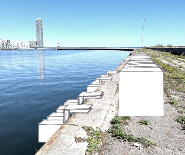 En række betonblokke langs kajen i Aarhus Havn under blå himmel.