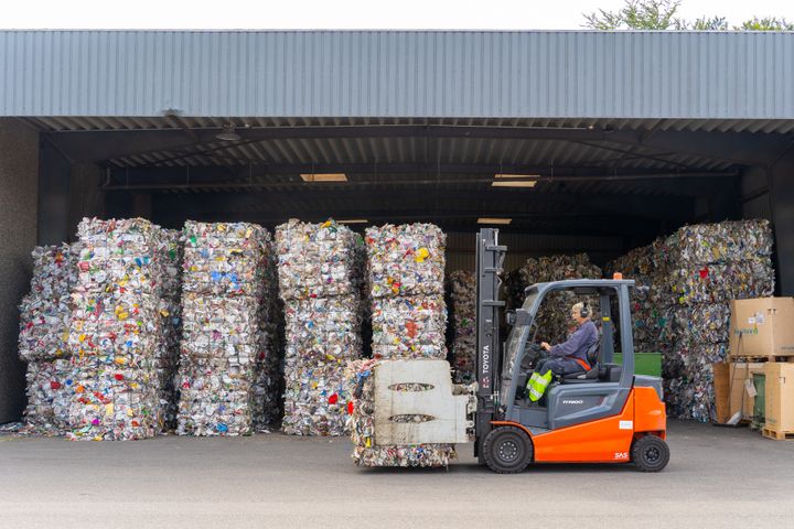 En gaffeltruck flytter stablet emballageaffald i en lagerbygning.