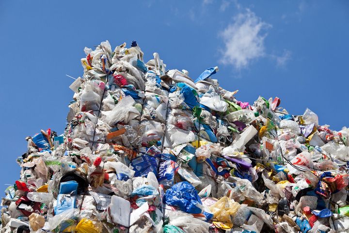 Stak af komprimeret fødevareemballage lavet af flere plastlag under en blå himmel.